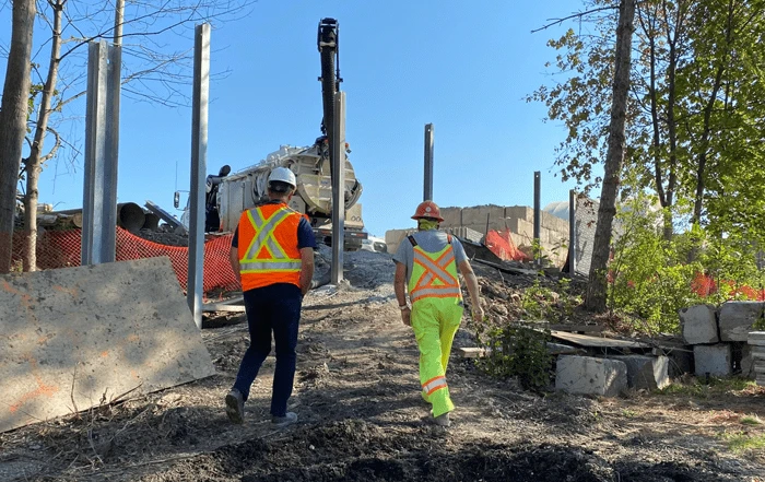 Two construction worker on site walking towards long metal beams