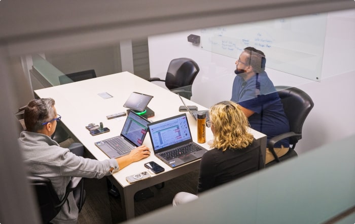 Three employees working together at laptops